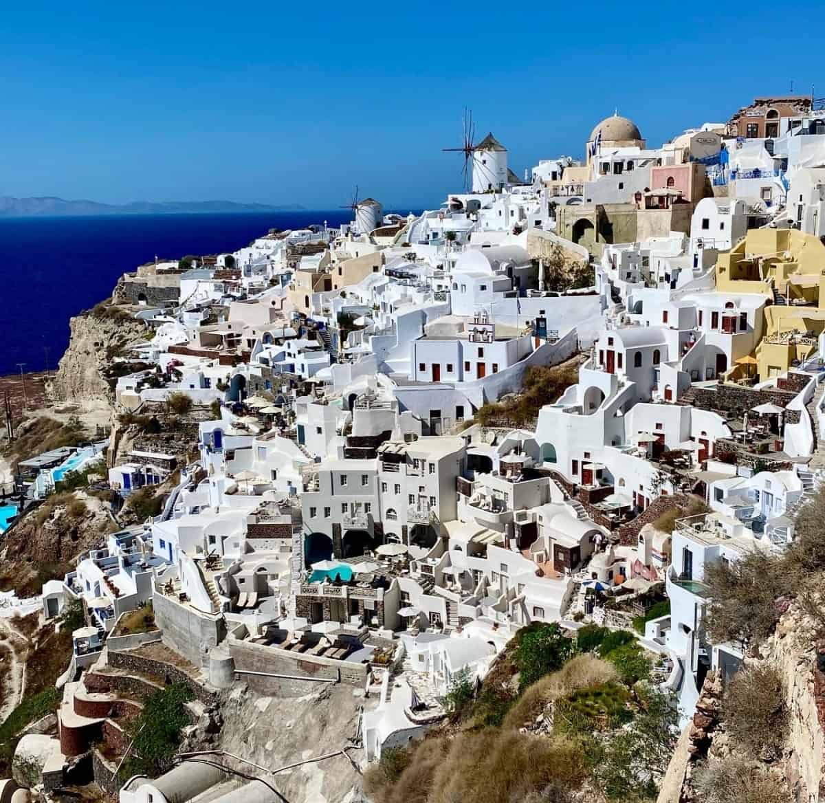 Is Oia worth visiting? A guide to Santorini's most famous town - the intense afternoon sun looking out at the windmills