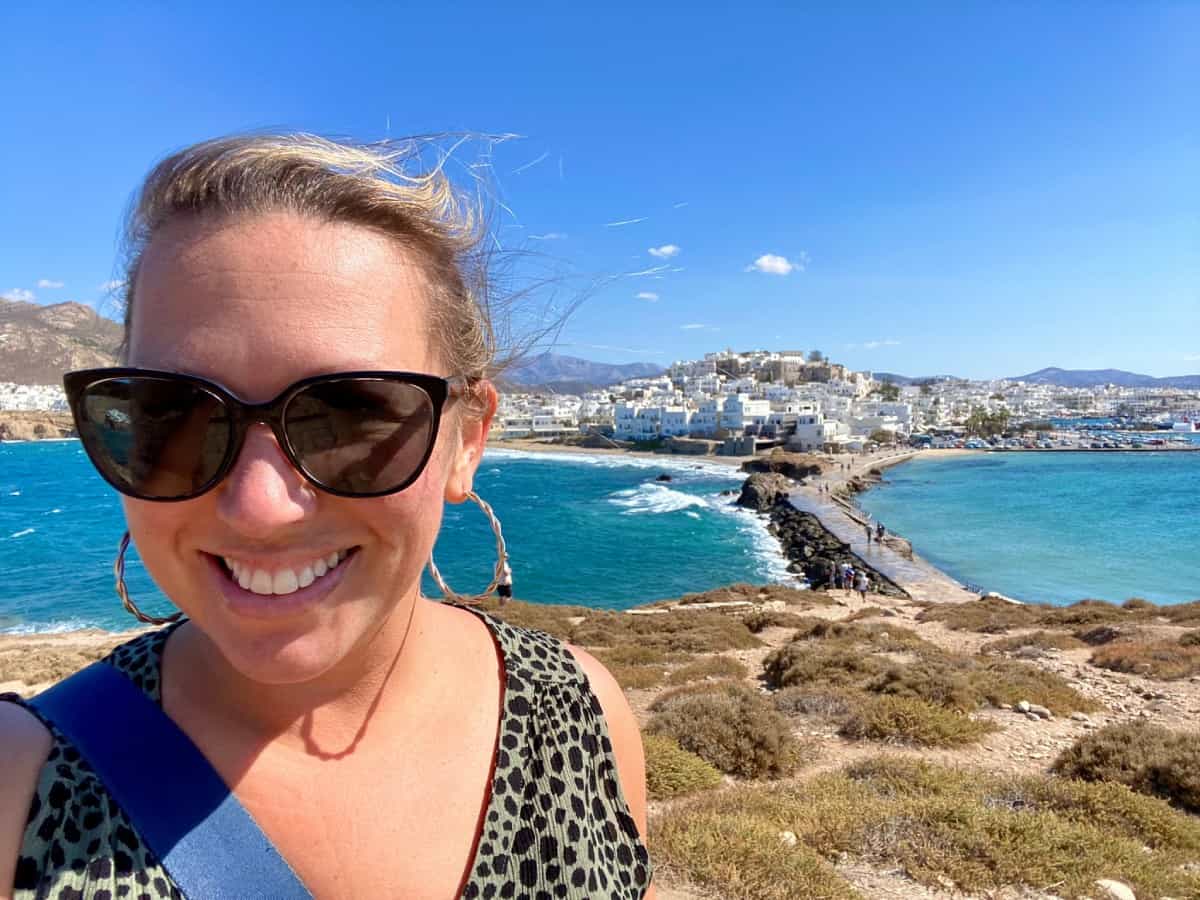 Girl smiling in front of Naxos Town - Where to Travel in 2024 | Here are 10 awesome ideas for 2024 travel destinations...from stunning landscapes to fascinating culture, epic train trips to quiet roadtrips & more! 