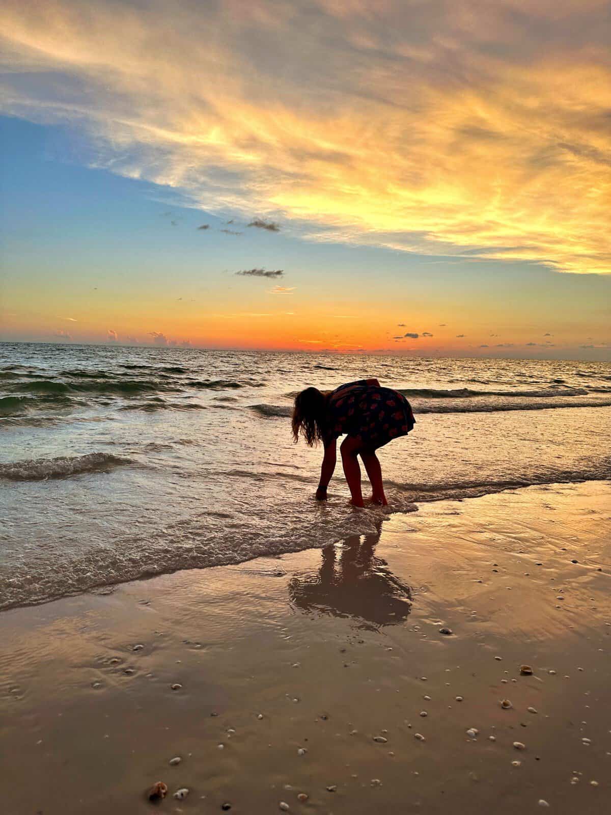 Marco Island is known for its sunsets, and the ones at JW Marriott Marco Island are amazing - silhouette of woman picking up shell beach at sunset